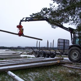 Traktori lastaa pylväitä kyytiin ja vie ne pystytettäviksi
