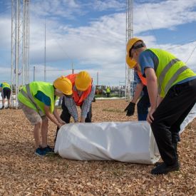 Telttakankaan purkua kääröltä. Mastot jo kurottavat taivaalle kuin kangasta odottaen.