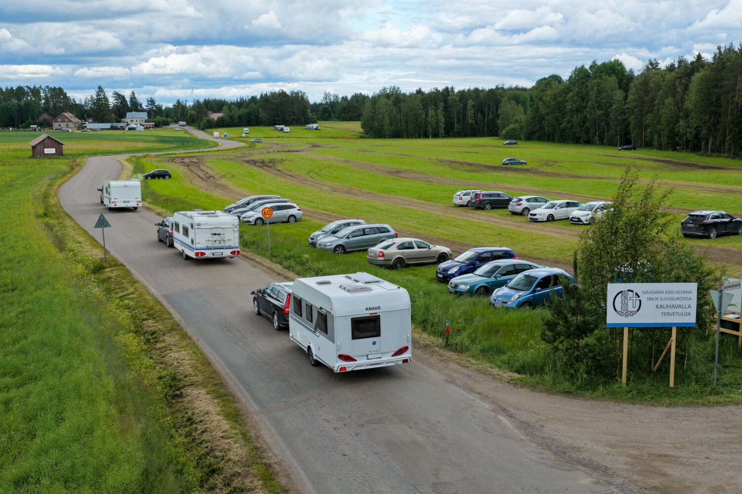 Asuntovaunu- ja autoyksiköitä peltojen välisellä tiellä.